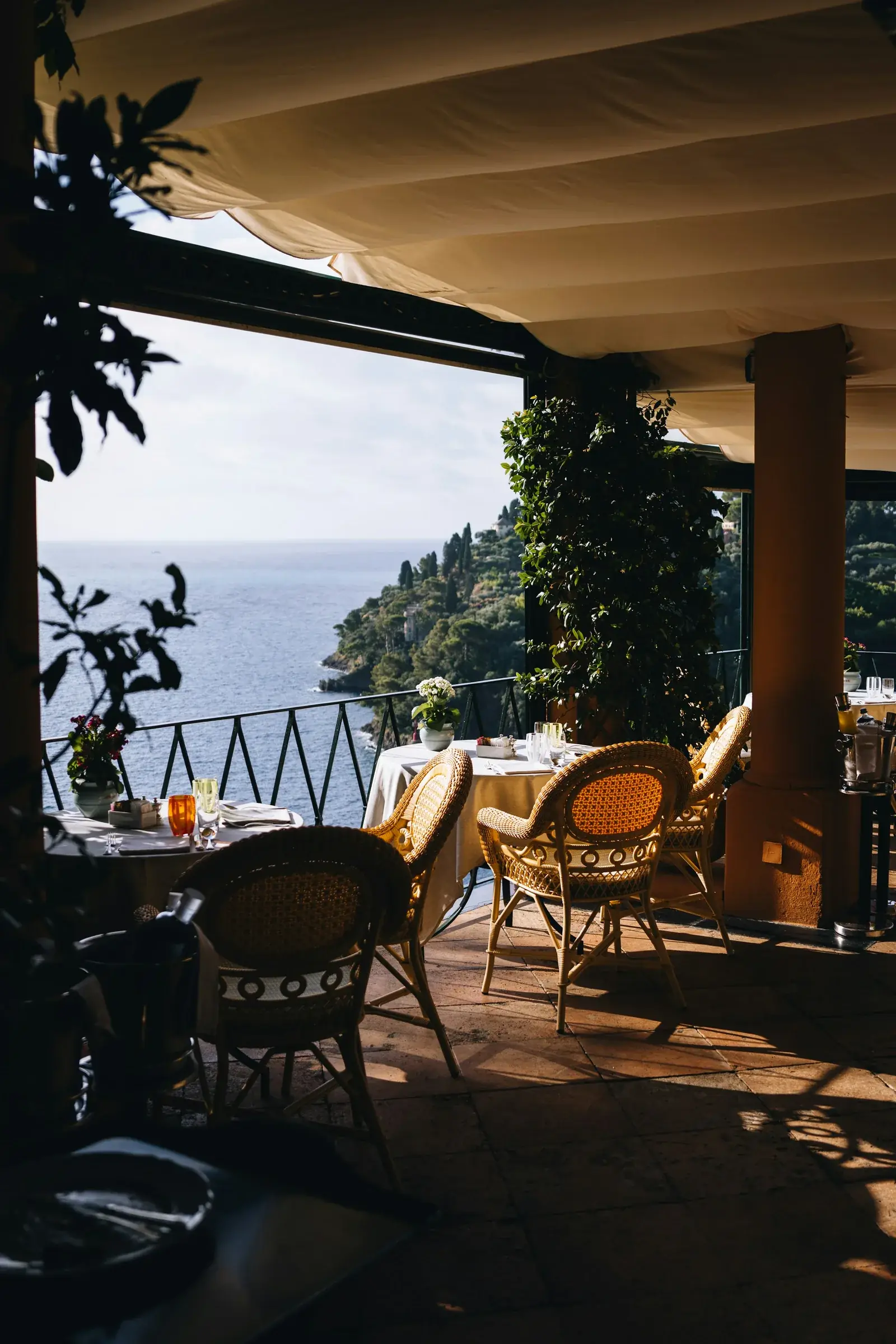 Esplanada de restaurante com mesas e vista para o mar.