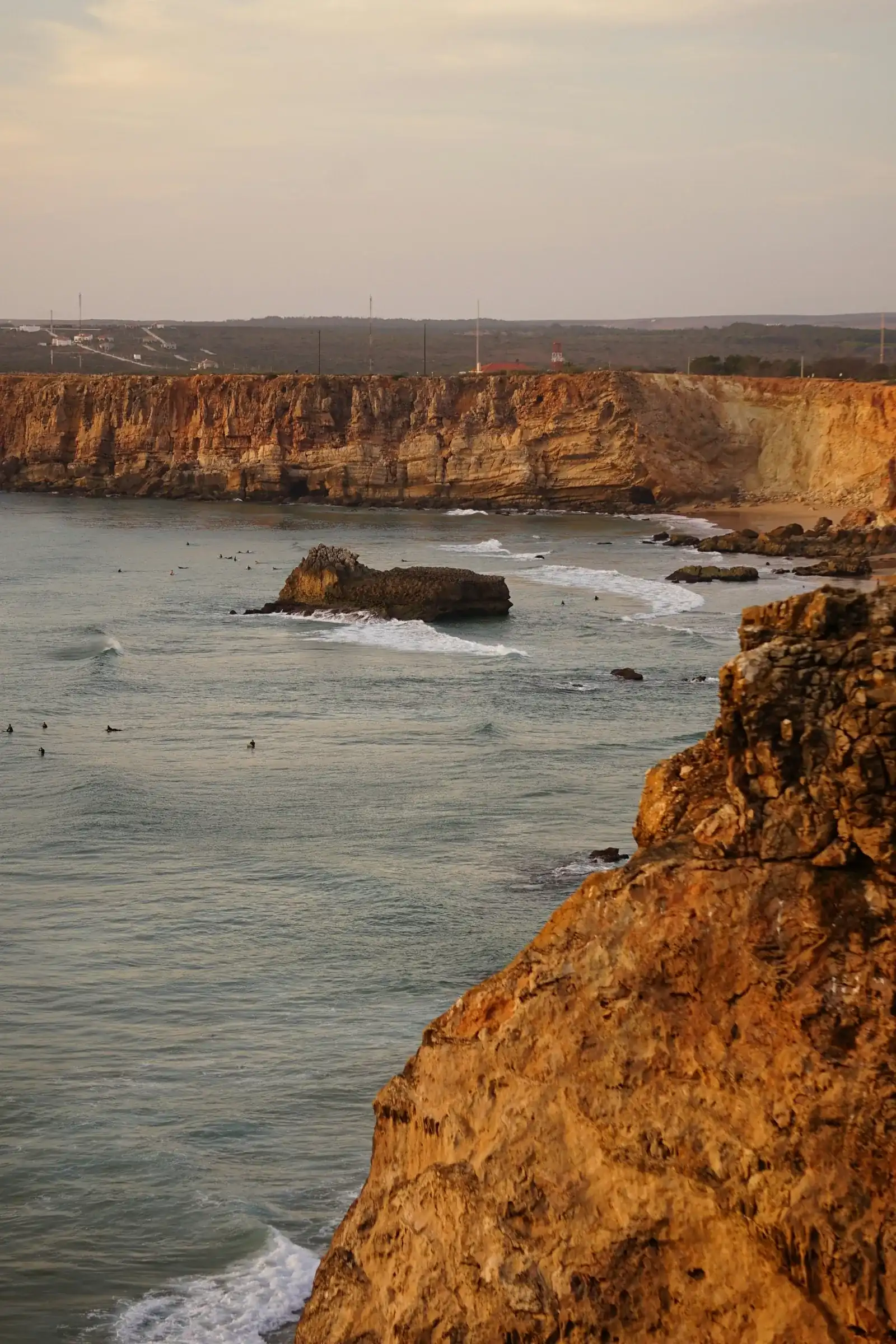 Surfistas no mar junto à costa rochosa de Sagres.